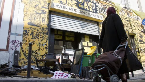 Eine Frau geht an dem mit Graffiti bedeckten „Lavoir Moderne Parisien“ vorbei.