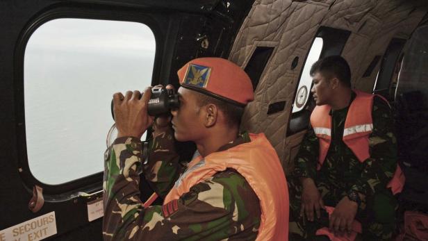Zwei Soldaten in einer Flugzeugkabine, einer blickt durch ein Fernglas aus dem Fenster.