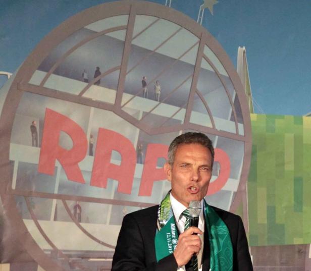 Ein Mann spricht vor einem Hintergrund mit der Aufschrift „RAPID“.