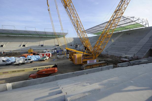 Eine Baustelle mit einem gelben Kran im Inneren eines Stadions.