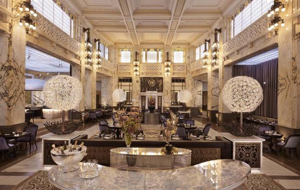 Ein prunkvoller Speisesaal mit Marmorsäulen und großen Kristallkugelleuchten.