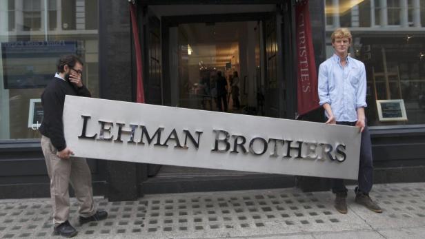 REUTERSChristies employees pose for a photograph with a Lehman Brothers sign at Christies in central London in this September 24, 2010 file photo. Lehman Brothers Holdings Incs record $639 billion bankruptcy ended on March 6, 2012, clearing the way for it