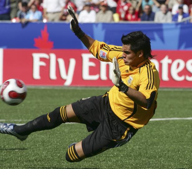 Ein Torwart in gelbem Trikot springt, um einen Fußball zu halten.