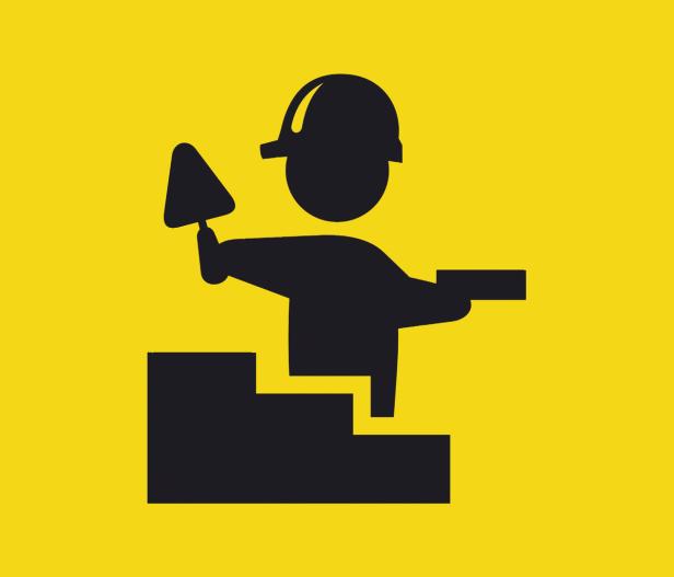 Ein Bauarbeiter mit Maurerkelle und Helm mauert eine Treppe.