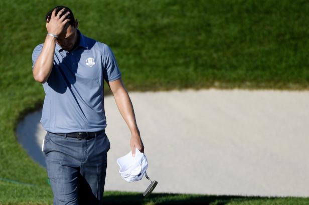 Ein Golfer hält sich frustriert den Kopf, während er über einen Golfplatz geht.