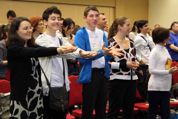 Eine Gruppe von Menschen steht in einem Raum und streckt die Hände aus.