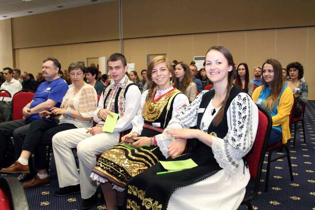 Eine Gruppe von Menschen sitzt in traditioneller Kleidung bei einer Veranstaltung.