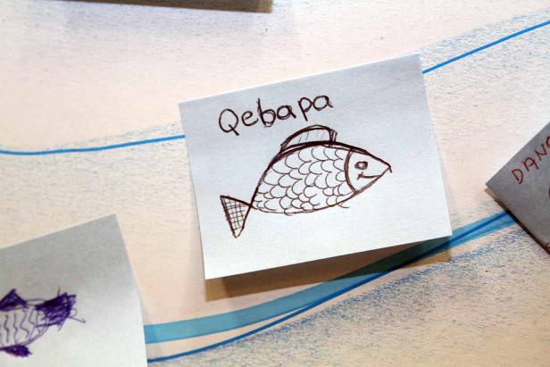 Eine Zeichnung von einem Fisch mit dem Wort „Qebapa“ darüber.