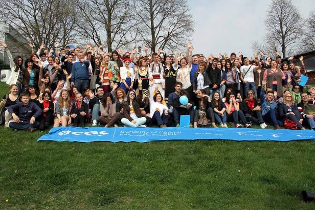 Eine große Gruppe von Menschen posiert auf einer Wiese für ein Foto.