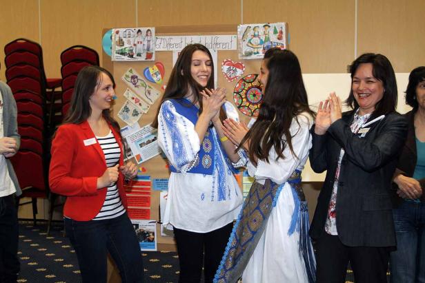 Frauen klatschen vor einer Pinnwand mit dem Motto „67 Different but not indifferent“.