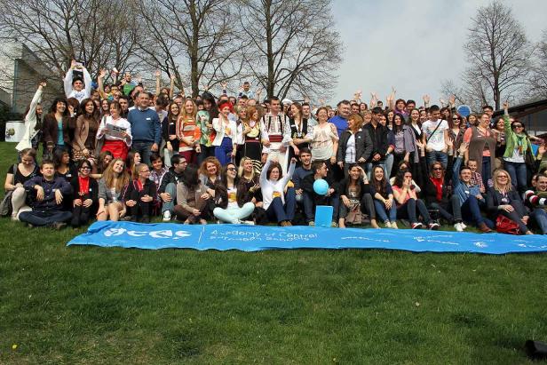 Eine große Gruppe von Menschen posiert auf einer Wiese für ein Foto.