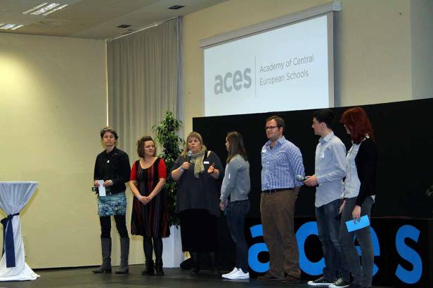 Eine Gruppe von Personen steht auf einer Bühne vor dem ACES-Logo.