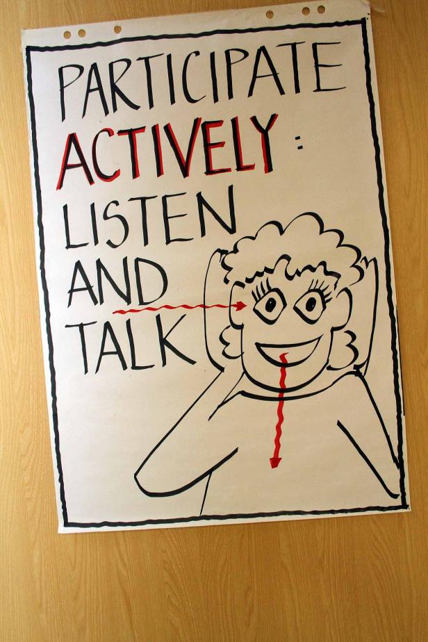 Ein handgezeichnetes Poster fordert zur aktiven Teilnahme auf: Zuhören und Sprechen.