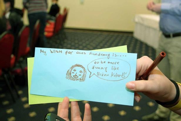 Eine Person hält eine Notiz mit der Aufschrift „Mein Wunsch für die Aces Academy ist, lustiger zu sein wie Heino Kiko!!“.