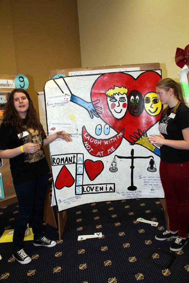 Zwei Frauen stehen vor einem Poster mit der Aufschrift „Laugh with me not at me“.