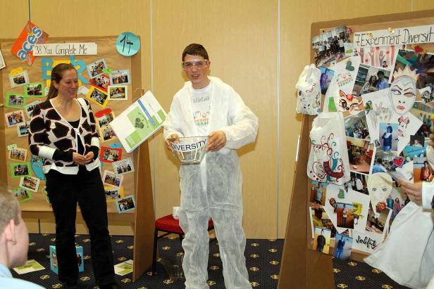 Ein Jugendlicher im Laborkittel hält eine Schüssel mit der Aufschrift „Diversity“.