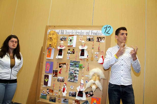 Ein junger Mann präsentiert eine Collage zum Thema Folklore und Freundschaft.