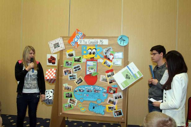 Eine junge Frau präsentiert mit Mikrofon eine Collage mit Fotos und Dekorationen.