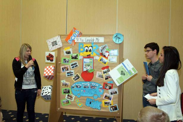 Eine Frau spricht vor einer Präsentation mit Fotos und dem Titel „38 You Complete Me“.