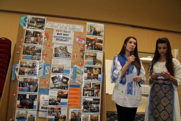 Zwei Frauen in traditioneller Kleidung präsentieren ein Projekt mit dem Titel „Different but not Indifferent“.