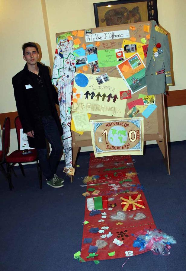 Ein junger Mann steht neben einer Präsentation zum Thema Vielfalt.