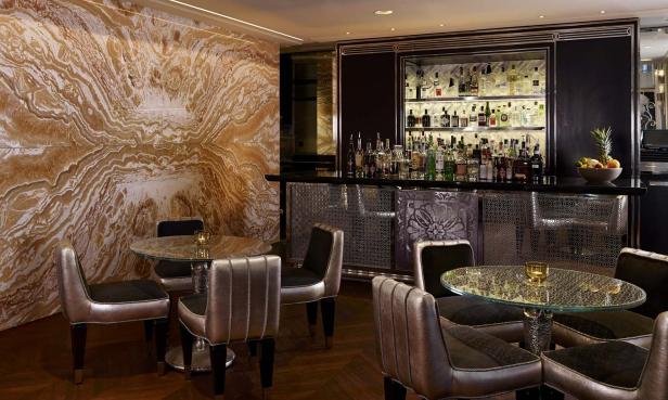 Eine Bar mit Tischen und Stühlen vor einer Wand mit auffälliger Marmorierung.