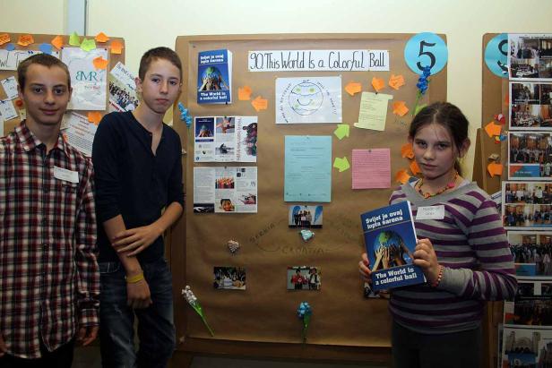 Drei Jugendliche stehen vor einer Pinnwand zum Thema „The World is a Colorful Ball“.