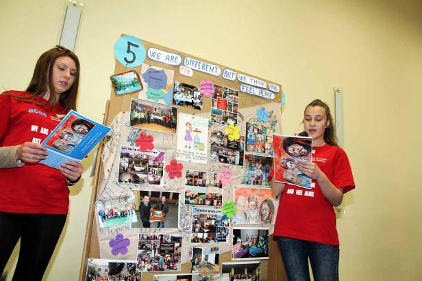 Zwei junge Frauen präsentieren ein Projekt zum Thema Vielfalt vor einer Pinnwand.