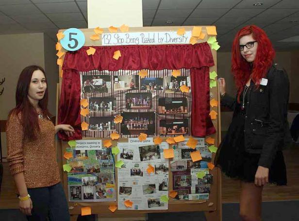 Zwei junge Frauen stehen vor einer Präsentationstafel zum Thema Diversität.