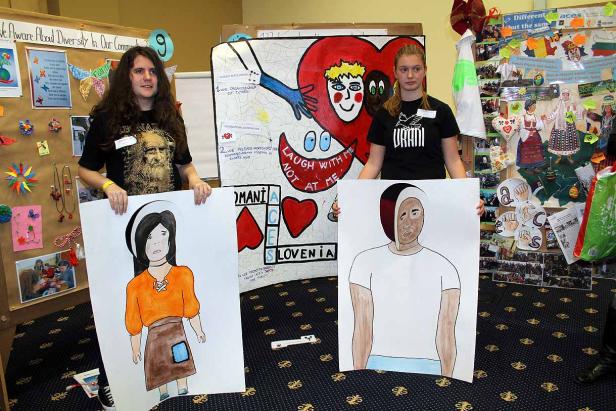 Zwei junge Frauen präsentieren Zeichnungen vor einem Stand zum Thema Vielfalt.