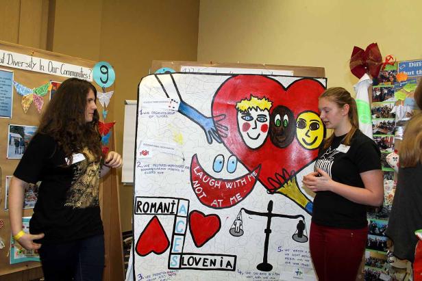 Zwei junge Frauen präsentieren ein Projekt über Vielfalt und internationale Zusammenarbeit.