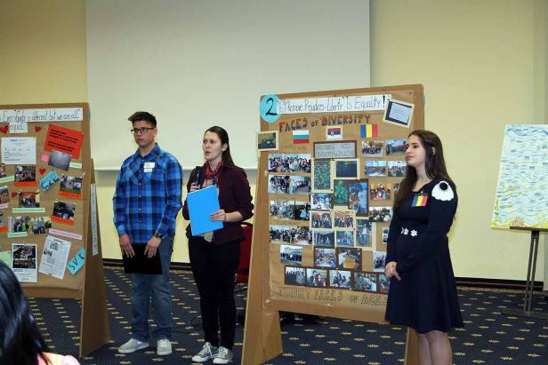 Drei Personen stehen vor Präsentationswänden zum Thema Vielfalt und Gleichberechtigung.