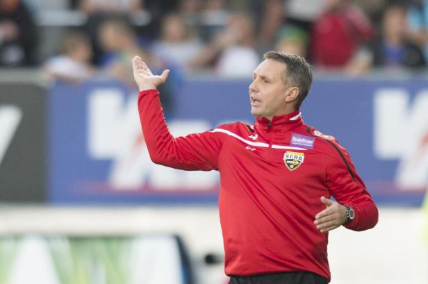 Ein Fußballtrainer gestikuliert während eines Spiels am Spielfeldrand.