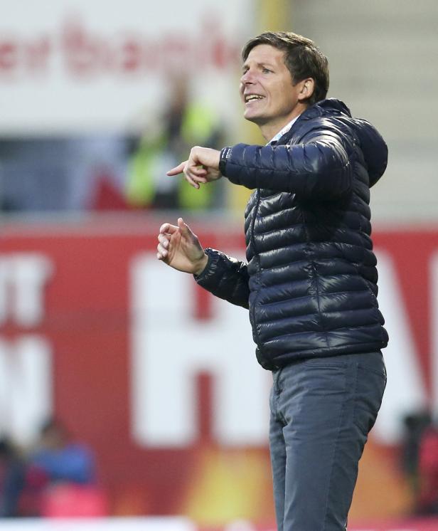 Ein Mann in einer blauen Jacke gestikuliert und scheint Anweisungen zu geben.