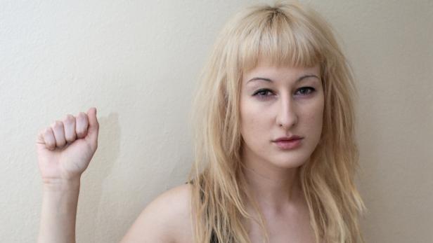Eine Frau mit blonden Haaren ballt ihre Faust.