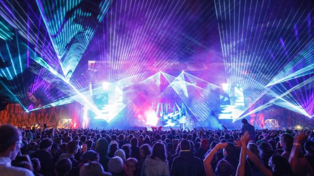 Eine große Menschenmenge genießt eine Musikveranstaltung mit Laserlichtshow.