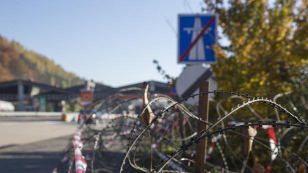 Ein mit Stacheldraht gesicherter Grenzübergang mit einem Schild, das das Ende einer Autobahn signalisiert.