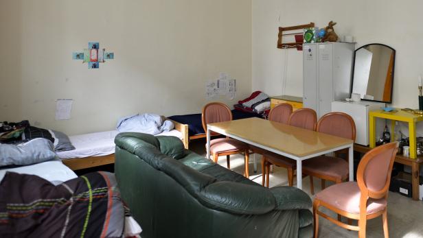 Ein Wohnheimzimmer mit Betten, einem Tisch und einem grünen Sofa.