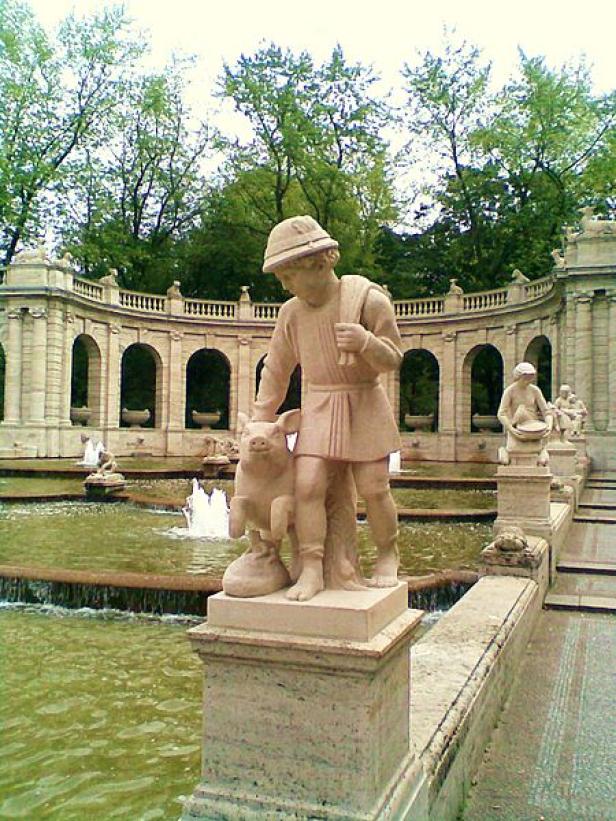 Eine Statue von einem Jungen mit einem Schwein in einem Brunnenpark.