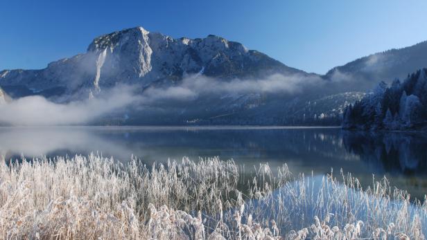 Der Altausseersee mit dem Jagdhaus auf der Seewiese wird Kulisse für eine Szene des 24. James Bond-Films 'Spectre' sein. Ein Bergsee mit schneebedeckten Bergen und frostbedecktem Gras im Vordergrund.