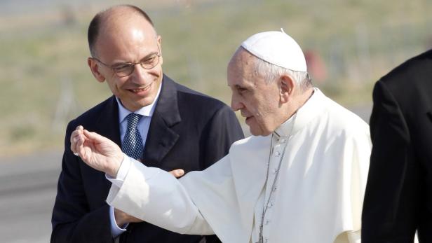 Papst Franziskus gestikuliert neben einem Mann im Anzug.