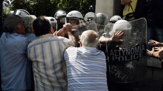 Eine Gruppe von Demonstranten drängt gegen eine Reihe von Polizisten mit Schutzschilden.