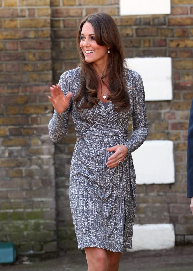 Kate Middleton lächelt und winkt in einem gemusterten Kleid.