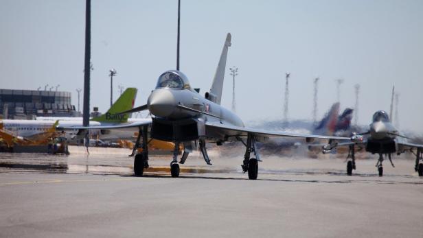 Zwei Eurofighter stehen auf einem Rollfeld vor weiteren Flugzeugen.