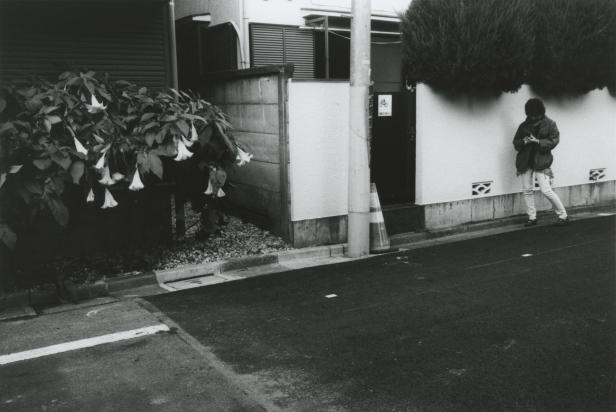 Eine Person steht an einer Straße in Japan und blickt auf ihr Handy.