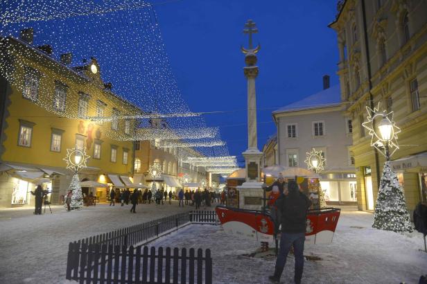 Ein verschneiter Platz in einer Stadt, geschmückt mit Lichtern zur Weihnachtszeit.