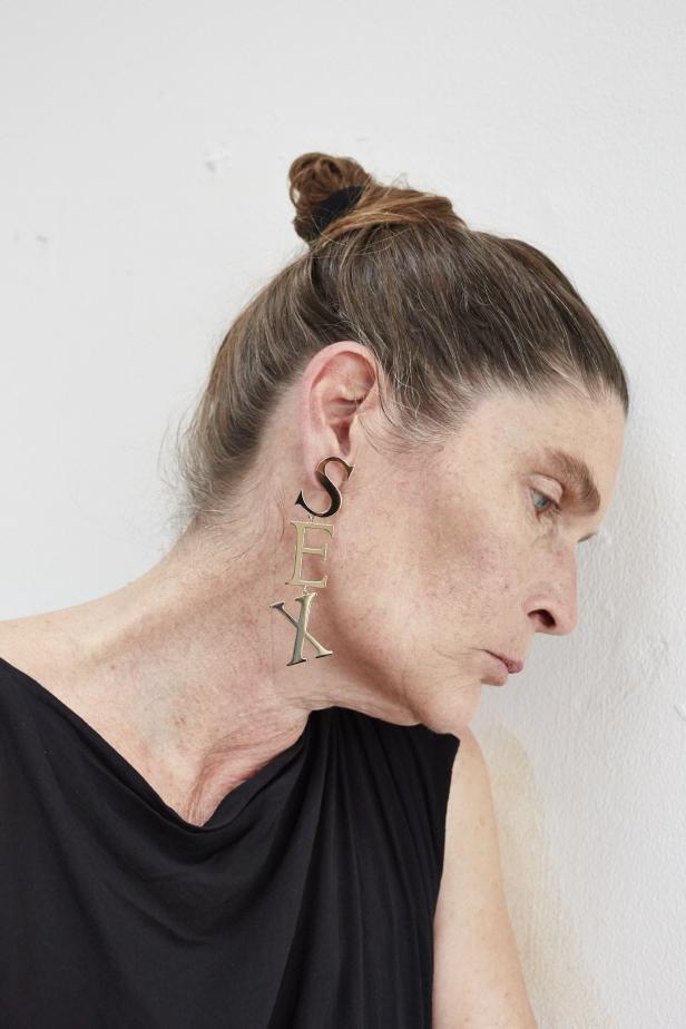 Eine Frau mit einem Ohrring, der das Wort „Sex“ buchstabiert.