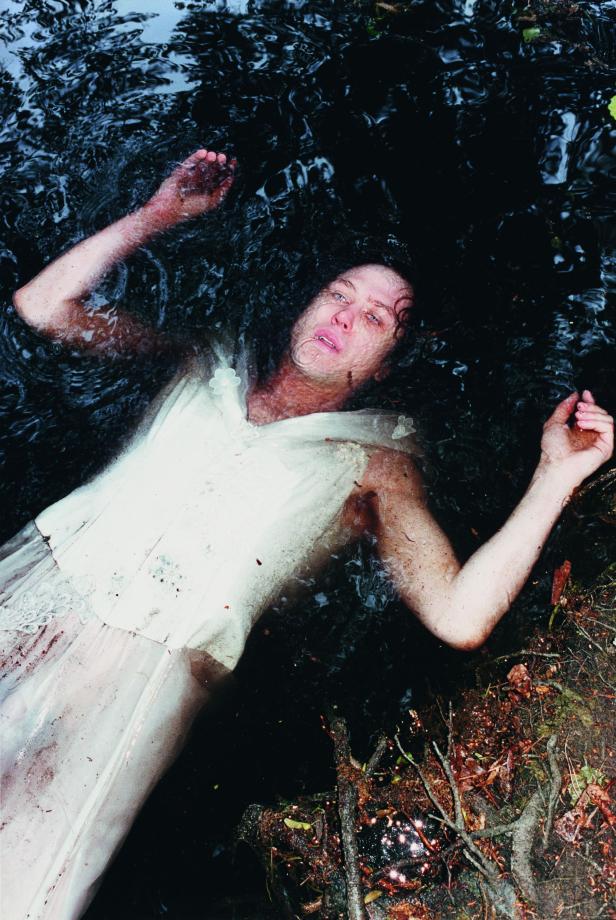 Eine Frau in einem weißen Kleid treibt im dunklen Wasser.