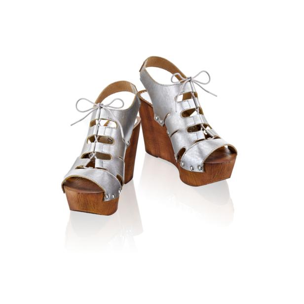 Ein Paar silberne Keilsandalen mit Holzboden und Schnürung stehen auf einem weißen Hintergrund.