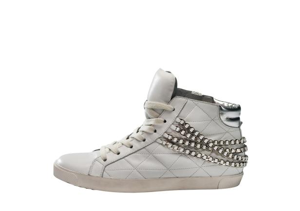 Ein weißer High-Top-Sneaker mit silbernen Ketten verziert.